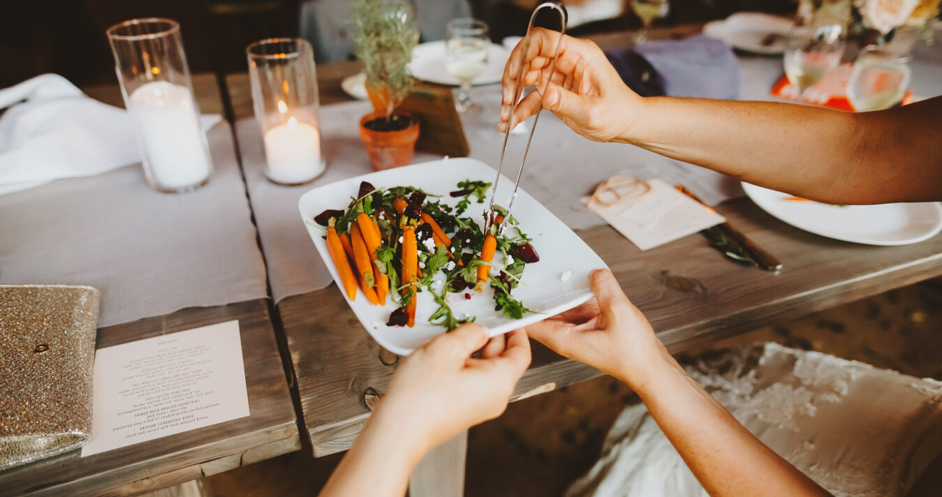 hands passing plate of carrots